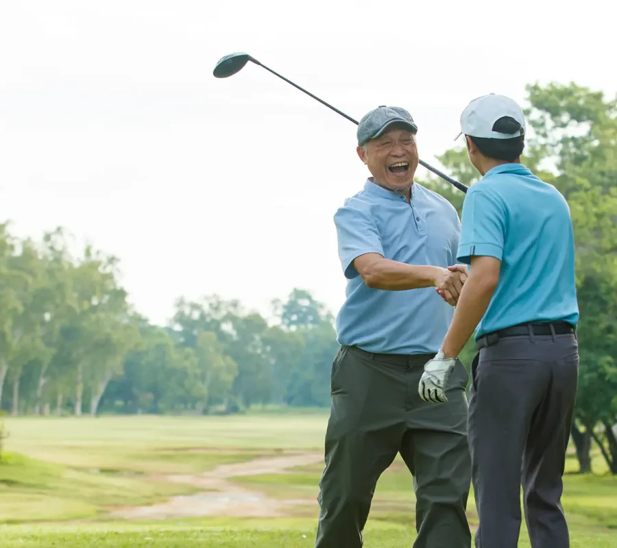 two men shake hands on a golf course