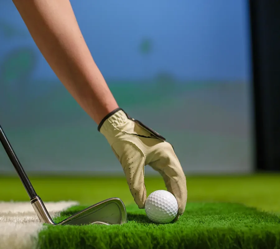 placing a golf ball on turf in an indoor golf simulator