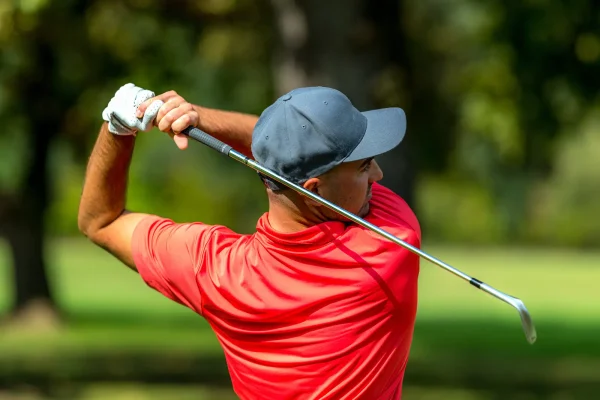 a man in a red shirt plays golf
